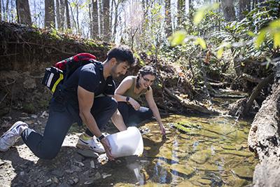 student taking water samples from creek